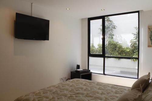 a bedroom with a bed and a large window at Suites Metropoli Bristol Parc in Quito
