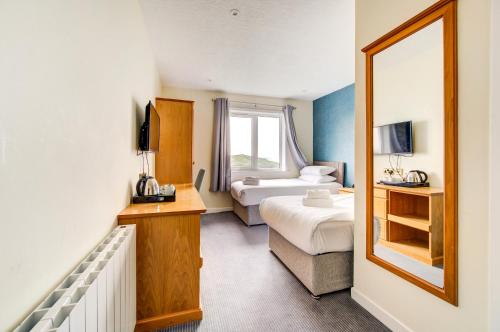 a hotel room with two beds and a mirror at The Morar Hotel in Morar