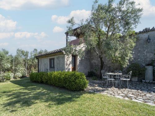 - une vue extérieure sur une maison avec une table et des chaises dans l'établissement Ancient holiday home in the countryside of Stilo with garden, à Guardavalle