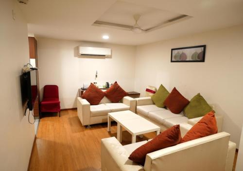 una sala de estar con sofás blancos y una silla roja. en Hotel Sasya Pride, en Kurnool