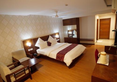 Habitación de hotel con cama grande y escritorio. en Hotel Sasya Pride, en Kurnool