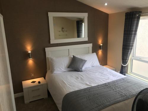 1 dormitorio con cama y espejo en la pared en Hot Tub Accommodation North Wales Lodge, en Rhyl