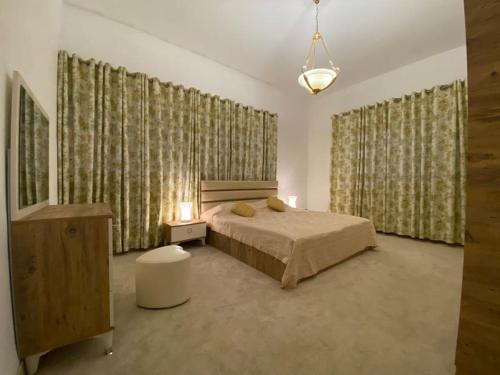een slaapkamer met een bed en twee ramen met gordijnen bij Lovely 3 Bedrooms Apartment at city center in Bayt Jālā