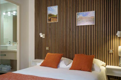 a bedroom with a bed with two orange pillows at Hôtel Restaurant Le Moulin de Saint Verand in Saint-Vérand