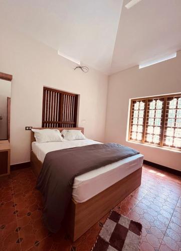 a bedroom with a large bed and two windows at Vasthyam in Kenichira
