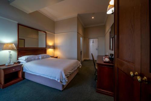 a bedroom with a bed and a desk with a lamp at The Balmoral in Durban