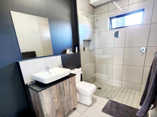 a bathroom with a sink and a toilet and a shower at Luxury Lowveld Apartment in Nelspruit