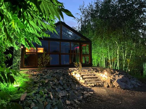 a glass house in the woods with lights on the rocks at Domki Platan w Karkonoszach in Kowary