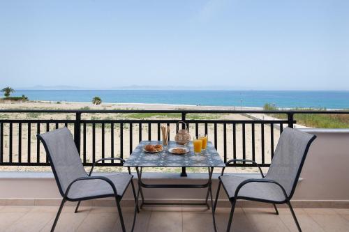 a table and chairs on a balcony with a view of the ocean at White&Blue luxury suites in Ialyssos
