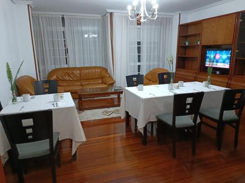 un comedor con mesas y sillas blancas y un sofá en Pensión A Fonte, en Caldas de Reis