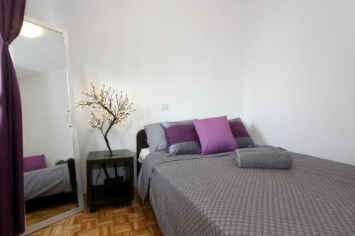 a bedroom with a bed with purple pillows and a mirror at Cezar Apartment in Belgrade