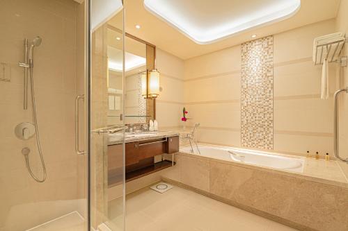 a bathroom with a tub and a sink and a shower at Shangri-La Jinan in Jinan