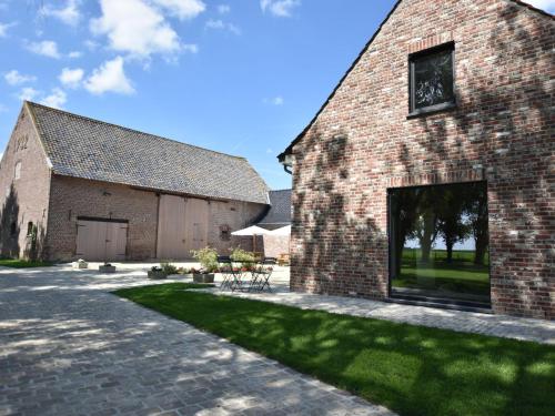 a brick barn with a patio and grass yard at Spacious Holiday Home with Pond in Poperinge in Roesbrugge-Haringe