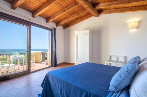1 dormitorio con cama azul y ventana grande en Villa Azzurra, en Stintino