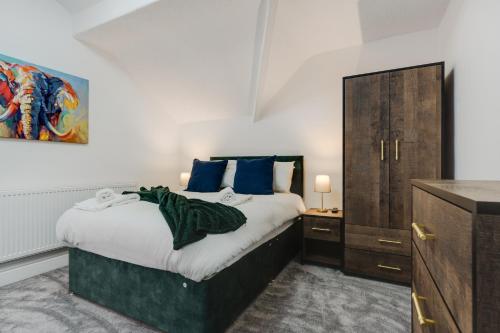 1 dormitorio con 1 cama grande con almohadas azules en St David's - Stylish 2 bed apartment, free parking, close to beach en Lytham St Annes