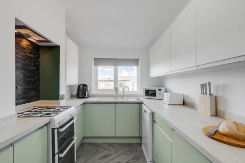 a kitchen with white cabinets and a stove top oven at Charles Alexander Short Stay - St Davids Rd North in Lytham St Annes