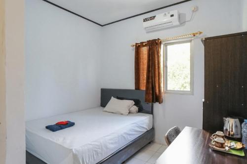 a small bedroom with a bed and a window at PAS Residence Sam Ratulangi Airport Mitra RedDoorz in Mapanget
