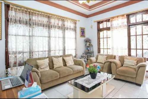 a living room with a couch and a laptop on a table at PAS Residence Sam Ratulangi Airport Mitra RedDoorz in Mapanget