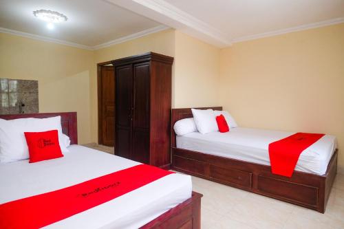 - une chambre avec 2 lits dotés de draps rouges et blancs dans l'établissement RedDoorz near Candi Ratu Boko 2, à Tanjungtirto