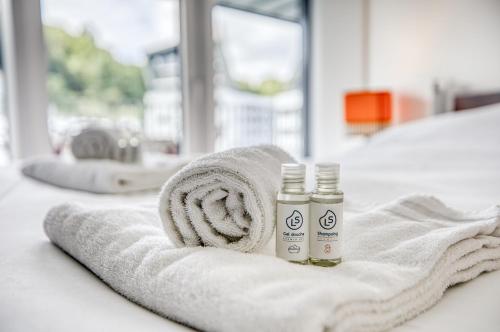 - deux bouteilles d'huiles essentielles assises sur une serviette sur un lit dans l'établissement View point Castle, à Annecy