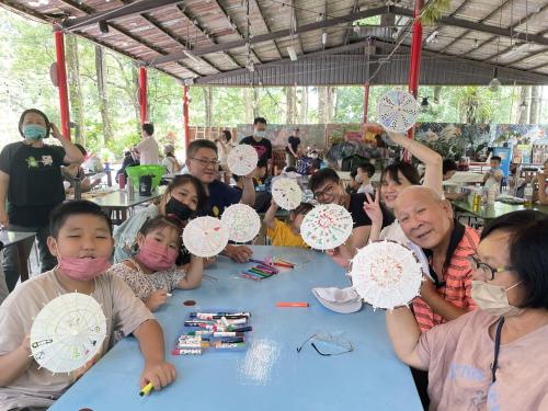 a group of people sitting at a table holding up paper umbrellas at De Wang Villa in Meinong