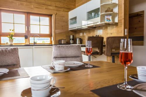 a wooden table with two glasses of wine on it at Chalet Hüttenzauber in Mehlmeisel