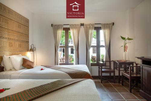 a hotel room with two beds and a desk at Victoria XiengThong Palace in Luang Prabang