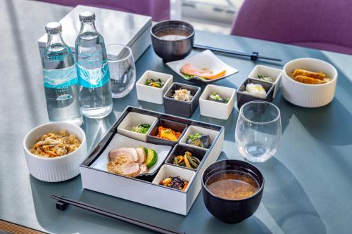 a table topped with bowls of food and bottles of water at Tokyu Stay Kamata - Tokyo Haneda in Tokyo