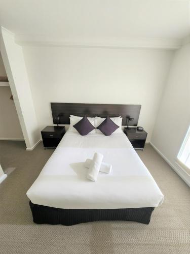 a bedroom with a large white bed with purple pillows at Oceanic on Thompson Apartments in Cowes