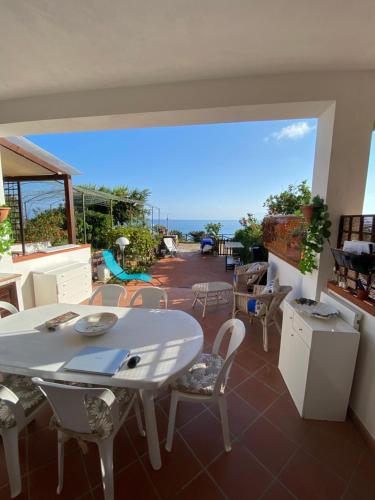 a patio with a white table and chairs and the ocean at Hibiscus Apartment-casa per le vacanze vicino tropea in Briatico