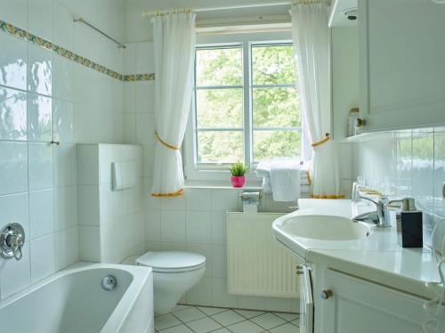 La salle de bains blanche est pourvue d'une baignoire, de toilettes et d'un lavabo. dans l'établissement Gasthof Menke, à Niederhaverbeck