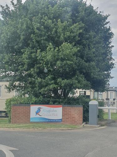 a tree with a sign in front of a building at Fantasy Island King Fisher 8Berth 402 in Ingoldmells