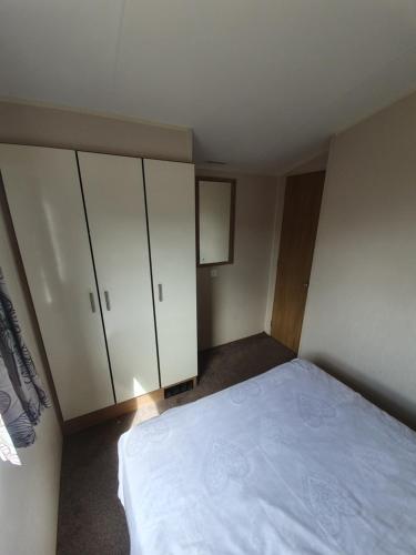 a bedroom with a bed and white cabinets at Fantasy Island King Fisher 8Berth 402 in Ingoldmells