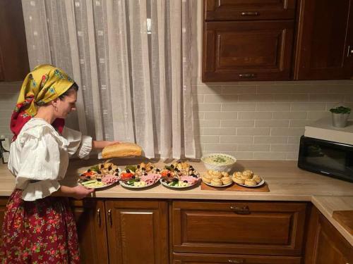 a woman standing in a kitchen with plates of food at Casa pintioi in Ieud