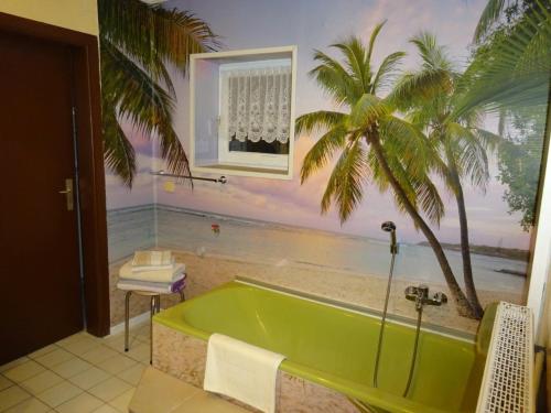 a bathroom with a green tub with a palm tree at Ferienwohnung Helm in Wilnsdorf