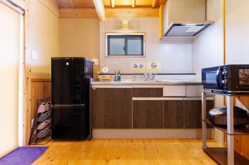 a kitchen with a black refrigerator in a room at 宇堅ビーチまで車で3分 琉球古民家を堪能できる貸切別荘 洋奈月 in Uruma