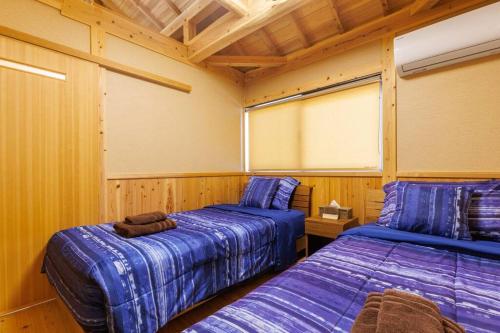 宇流麻宇堅ビーチまで車で3分 琉球古民家を堪能できる貸切別荘 洋奈月的一间木墙房间里有两张床