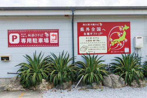 two signs on the side of a building with plants at 宇堅ビーチまで車で3分 琉球古民家を堪能できる貸切別荘 洋奈月 in Uruma