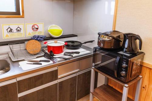 a kitchen with a stove top and a microwave at 宇堅ビーチまで車で3分 琉球古民家を堪能できる貸切別荘 洋奈月 in Uruma
