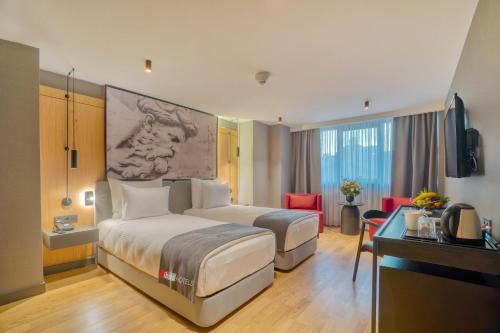 um quarto de hotel com duas camas e uma secretária em Ibos Hotels Izmir Alsancak em Alsancak