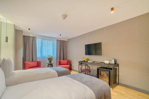 a hotel room with two beds and a television at İbos Hotels Izmir in Izmir