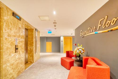 a lobby with orange furniture and a welcome sign at İbos Hotels Izmir in Izmir