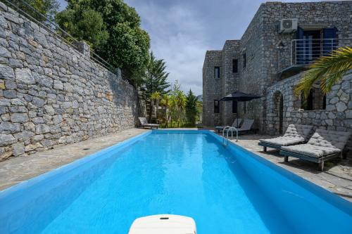 a large blue swimming pool next to a stone wall at Petritis in Lambiní