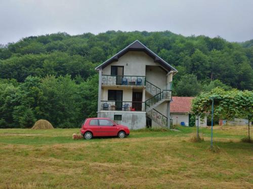 a small red car parked in front of a house at Apartmani Jana in Bijelo Polje