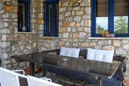 a table and chairs in front of a stone wall at Manousaki in Lambiní