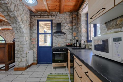 a kitchen with a white microwave and a blue door at Rozare in Lambiní