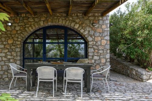 a patio with a table and chairs in a stone wall at Rozare in Lambiní