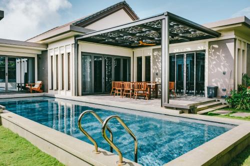 uma piscina em frente a uma casa em 04-Biệt thự Villa cao cấp Hồ Tràm 350m2 sân vườn 1000M2, BBQ, cầu ngắm biển, 200m đi bộ I Luxury Villa 350m2 in Ho Tram Beach, garden, privite pool, 200m walk to beach em Xuyên Mộc