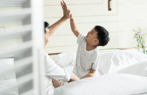 a woman giving a child a high five in a bed at Four Seasons Hotel Singapore in Singapore