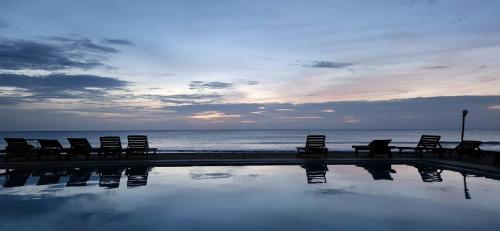 a group of chairs sitting next to the ocean at Hotel Coral Bay in Trincomalee